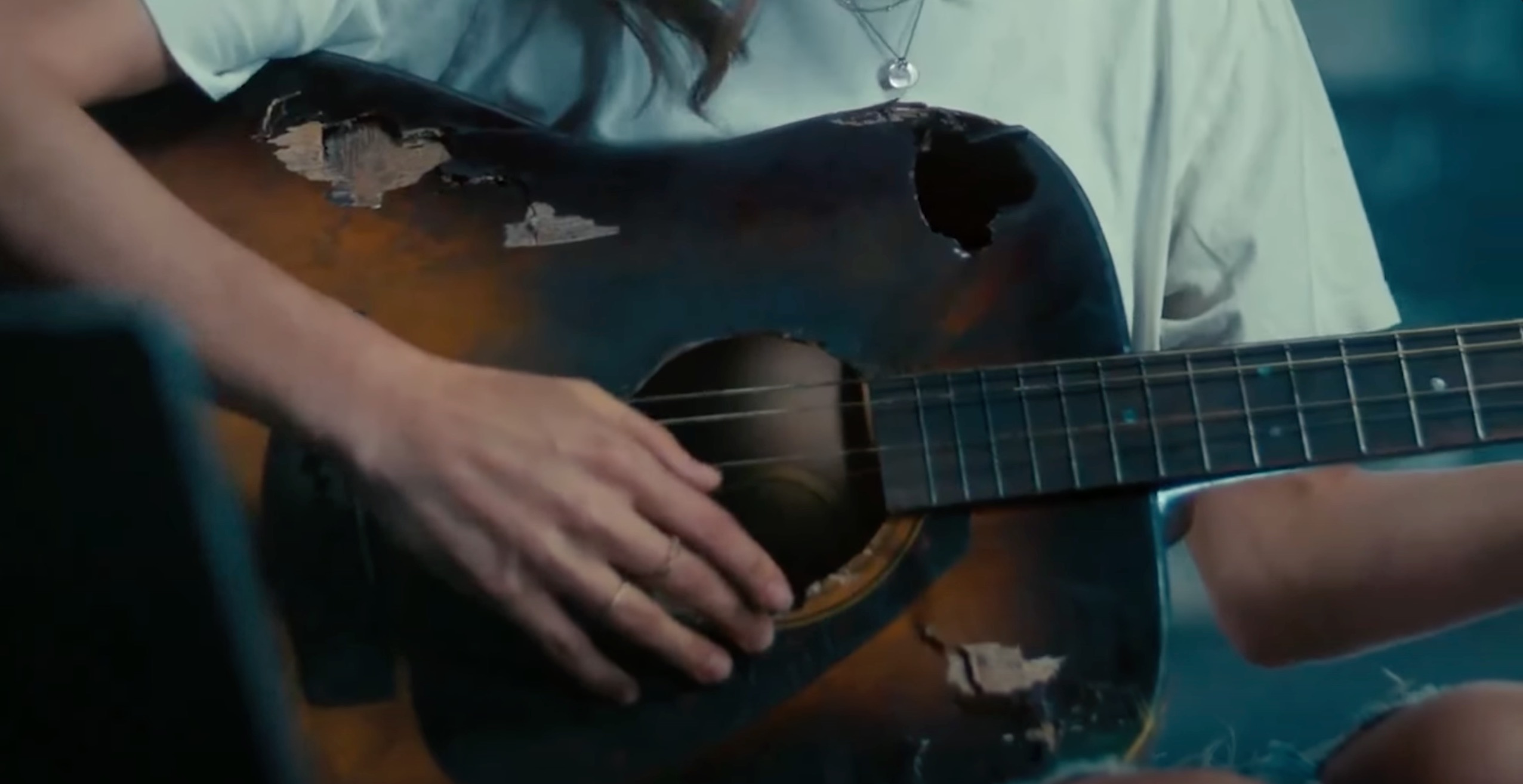 Im Werbeclip betritt eine Frau einen Raum voller zerstörter Gegenstände, hebt eine kaputte Gitarre mit nur wenigen verbliebenen Saiten auf und spielt eine Melodie, die anscheinend als Notenblatt auf einem Samsung-Galaxy-Tablet dargestellt wird. Autsch-Finger-Marketing: Samsung kontert „Crush“-iPad-Werbeclip